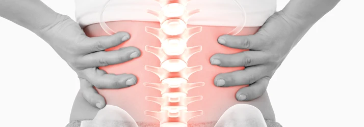 Person holding the lower back with both hands, with the spine and lower back highlighted in red.